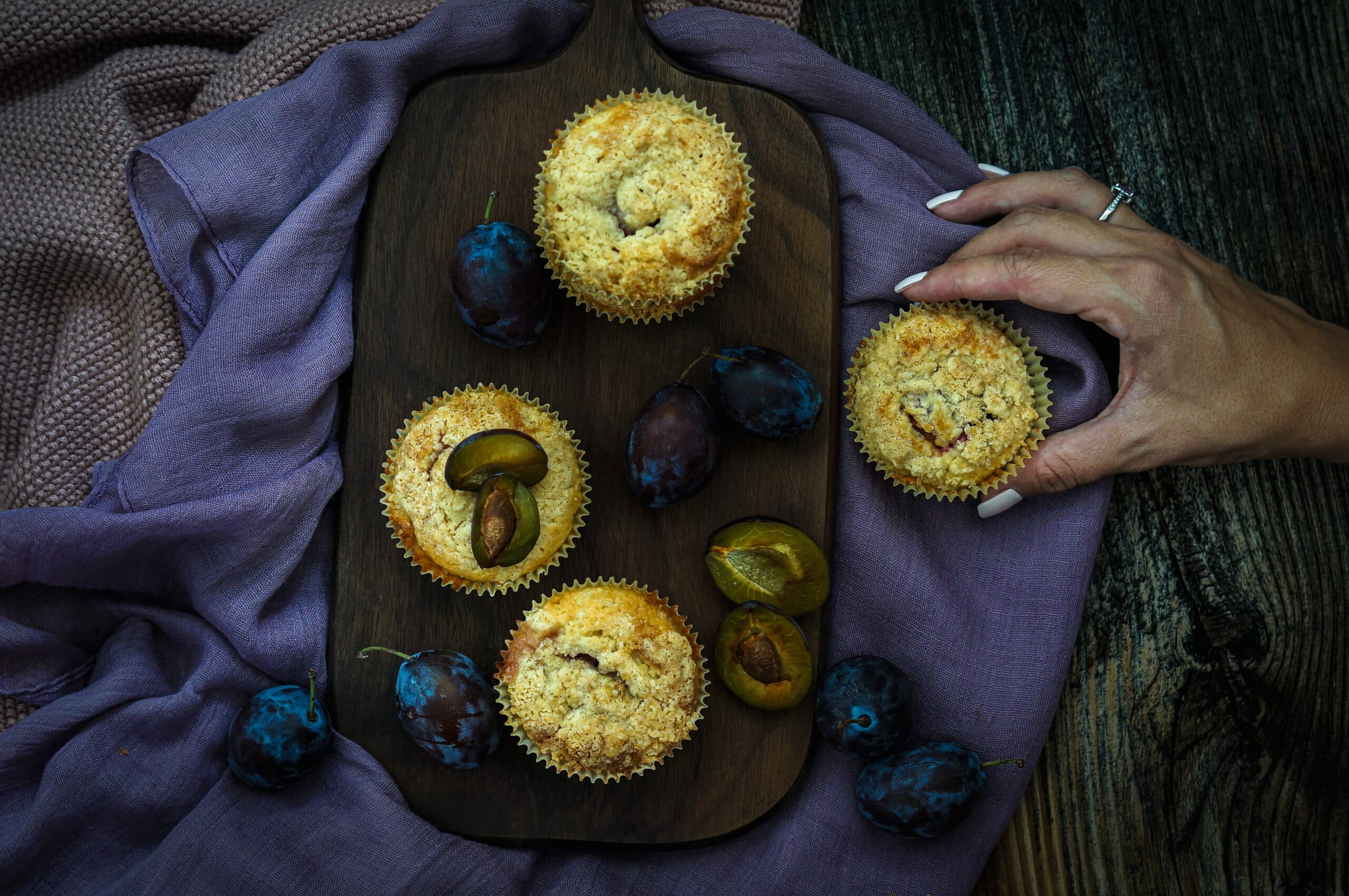 Hand welche ein Zwetschgen Crumble Muffins hält